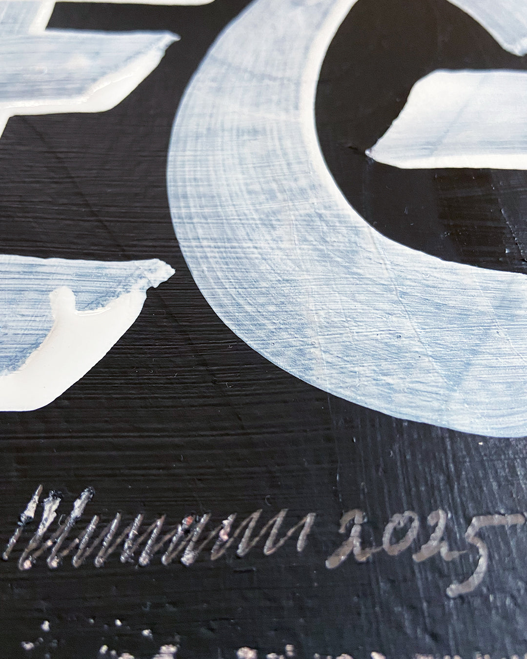 Detail der Signatur eines Mixed-Media-Unikats, ungerahmt auf hellgrauem Hintergrund
