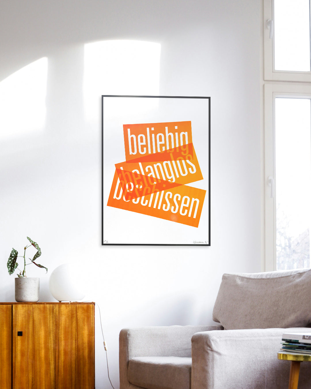 Siebruck mit den Worten »beliebig«, »belanglos« und »beschissen« in Neonorange, gesetzt in schmaler Groteskschrift auf weißem Karton, gerahmt mit schwarzem Rahmen an Zimmerwand, im Vordergrund ein grauer Sessel und eine braune Kommode