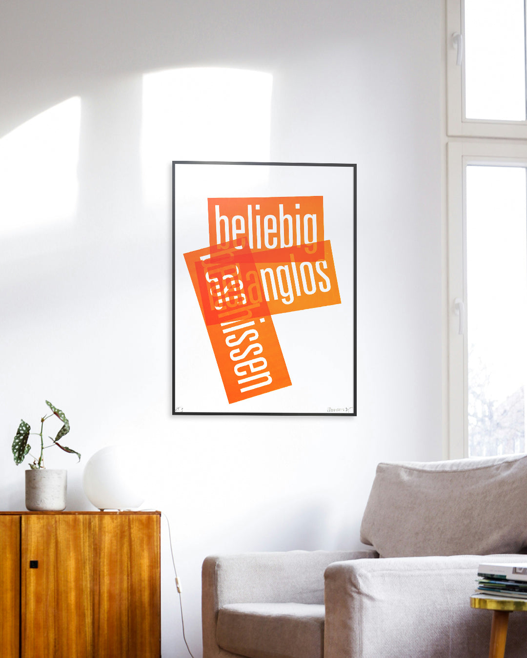 Siebruck mit den Worten »beliebig«, »belanglos« und »beschissen« in Neonorange, gesetzt in schmaler Groteskschrift auf weißem Karton, gerahmt mit schwarzem Rahmen an Zimmerwand, im Vordergrund ein grauer Sessel und eine braune Kommode