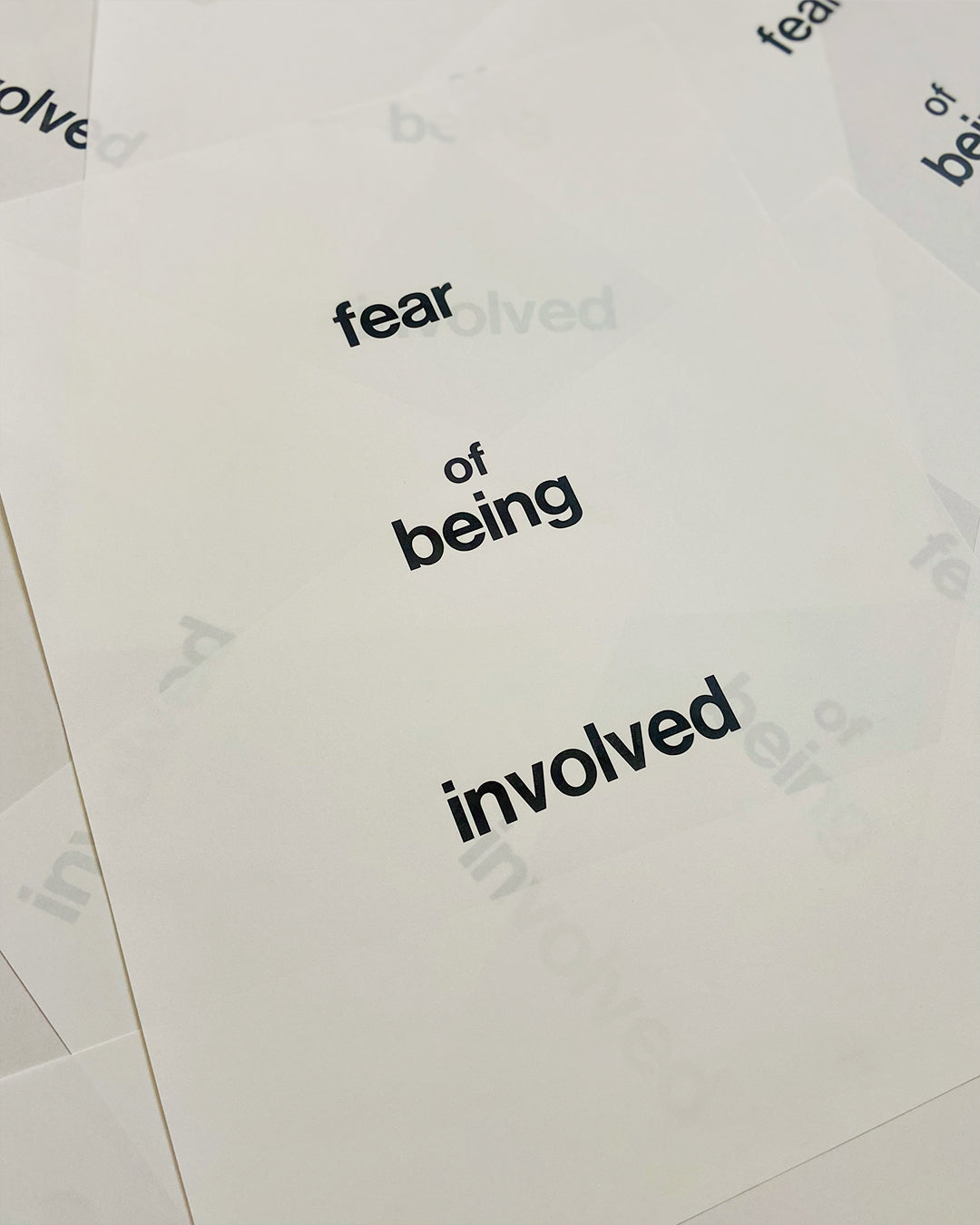 Mehrere unsortierte Exemplare des limitierten Bleisatz-Druckes mit den Worten ”fear of being involved“ in schwarzer Groteskschrift auf Gmund Lakepaper (90 g/m²) im Format 30 × 40 cm