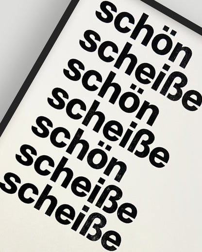 Nahaufnahme eines RISO-Druckes mit den Worten »schön« und »scheiße« in schwarzer Groteskschrift auf cremefarbenen Papier, gerahmt mit schwarzem Rahmen vor hellgrauem Hintergrund, nummeriert und signiert