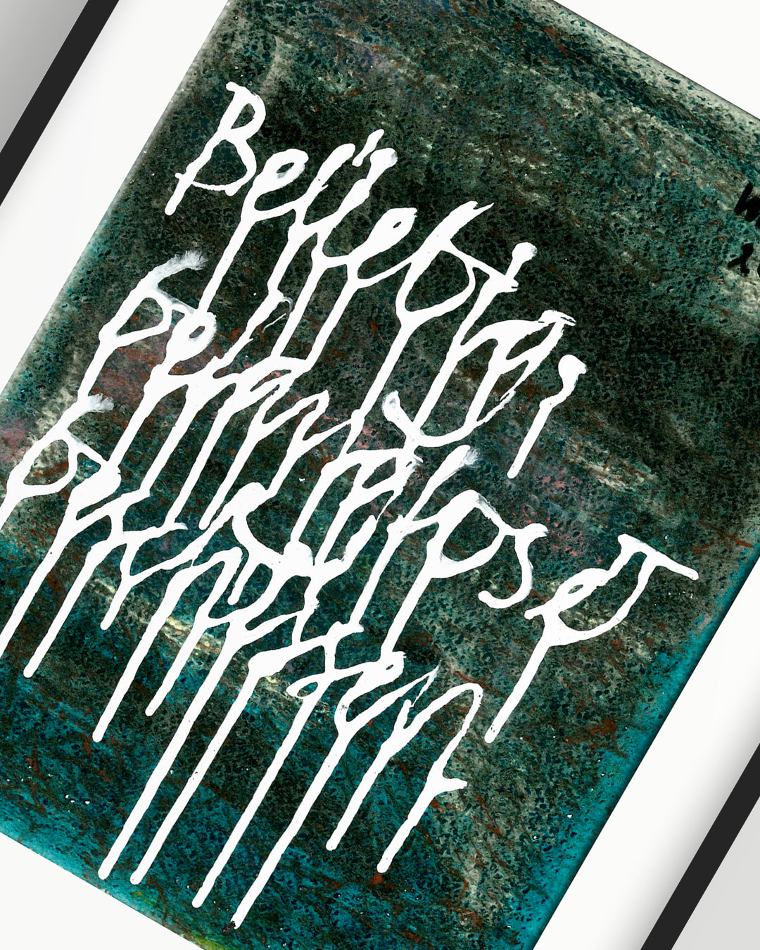 Nahaufnahme eines chirografischen Mixed-Media-Unikats mit den Worten „Beliebig, belanglos & beschissen“ auf Karton, gerahmt mit schwarzem Rahmen und Passepartout auf hellgrauem Hintergrund, signiert