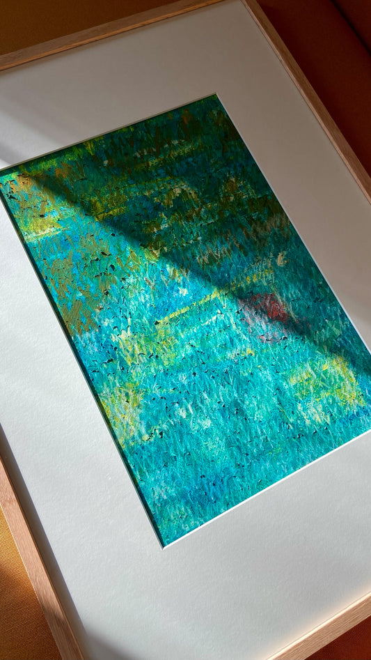 Mehrfarbige Chirografie in Ölpastell und Kreide auf Karton, gerahmt mit Passepartout und Holzrahmen, liegend auf gelbem Polster, partiell mit Sonnenlicht beleuchtet