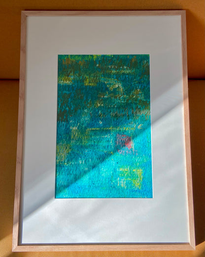 Mehrfarbige Chirografie in Ölpastell und Kreide auf Karton, gerahmt mit Passepartout und Holzrahmen, lehnend auf gelbem Polster, partiell mit Sonnenlicht beleuchtet
