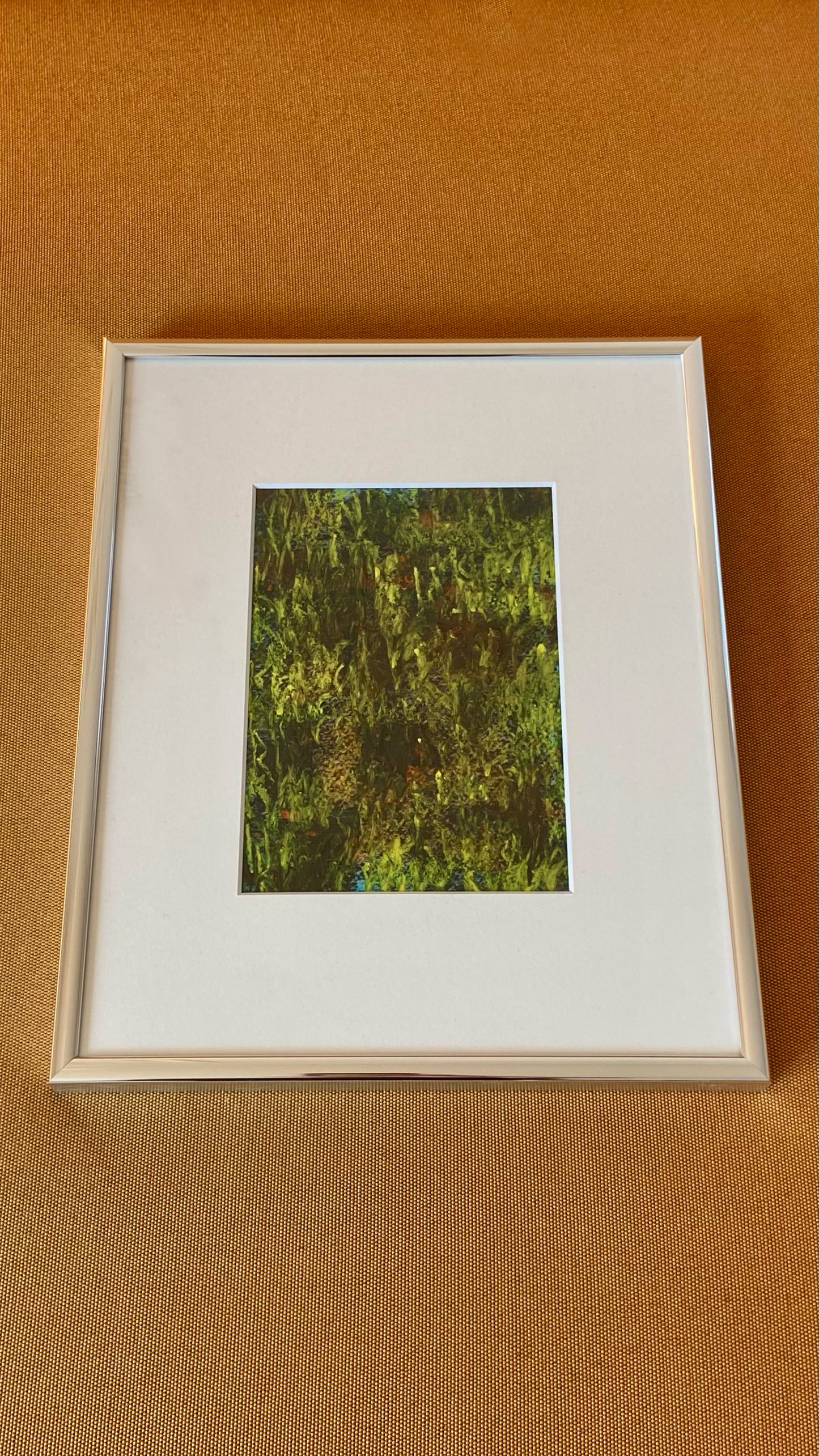 Mehrfarbige Chirografie in Kreide und Ölpastell auf Karton, gerahmt mit Passepartout und Aluminiumrahmen, liegend auf gelbem Polster