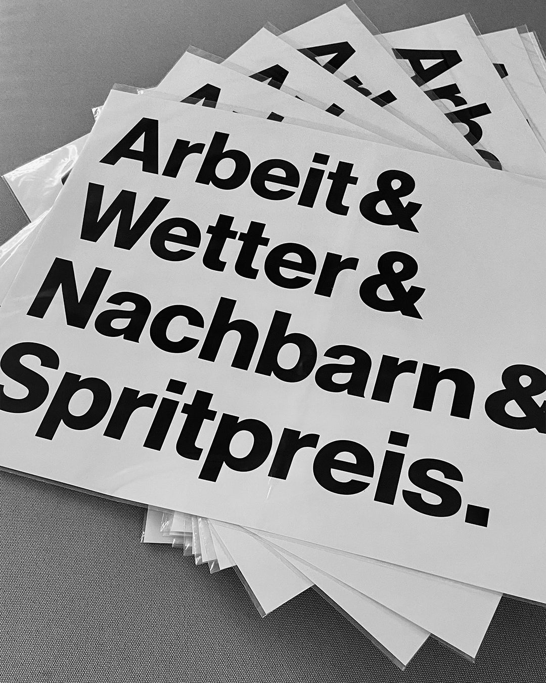 Mehrere Exemplare des Siebdrucks »Arbeit & Wetter & Nachbarn & Spritpreis.« auf hochwertigem Papier.