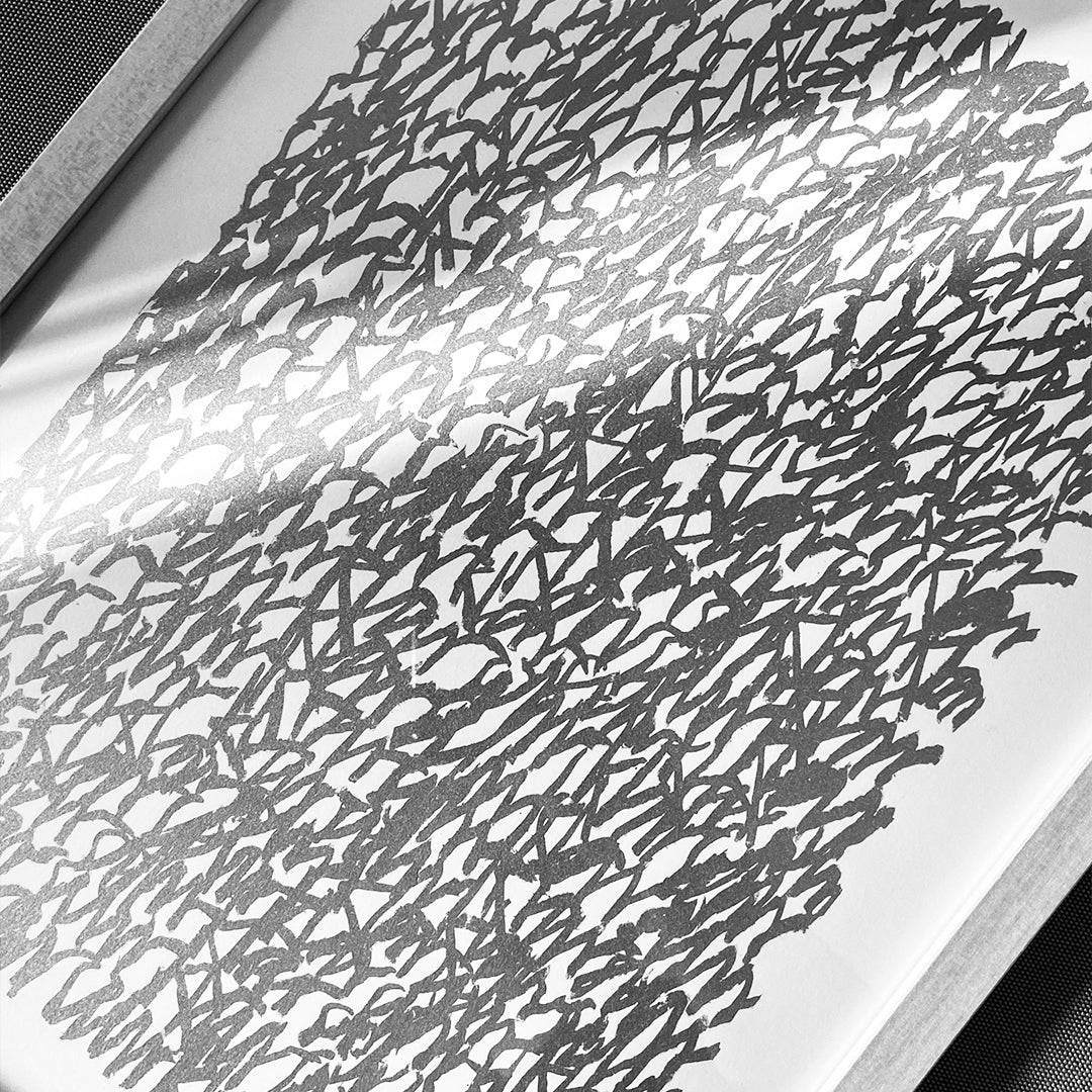 Gerahmter chirografischer Siebdruck in Schwarzweiß mit sichtbarer Papierstruktur und abstraktem Schriftbild.