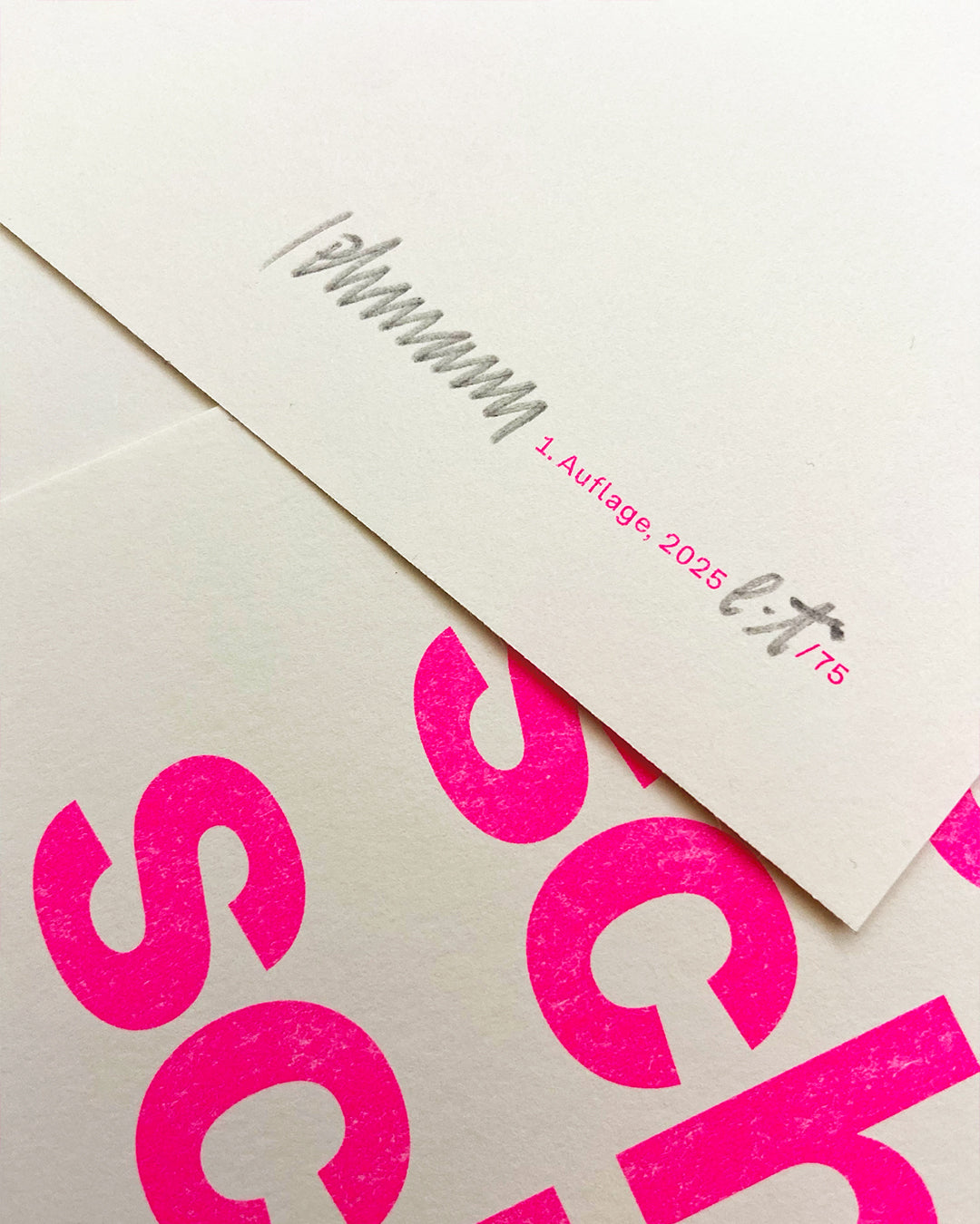 Detailaufnahme des RISO-Druckes der pinken Groteskschrift und der Signatur auf cremefarbenen Papier